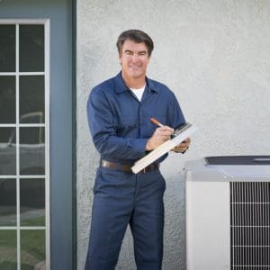 A man holding a clipboard in front of an air conditioner.