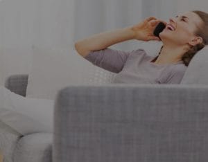 A woman sitting on a couch talking on a cell phone.