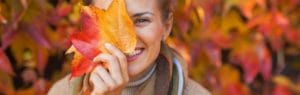 A woman is holding a leaf in front of her face.
