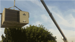 An air conditioning unit being lifted by a crane.