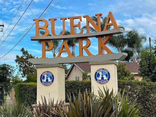 City entrance sign for buena park with decorative plants and clear skies in the background.